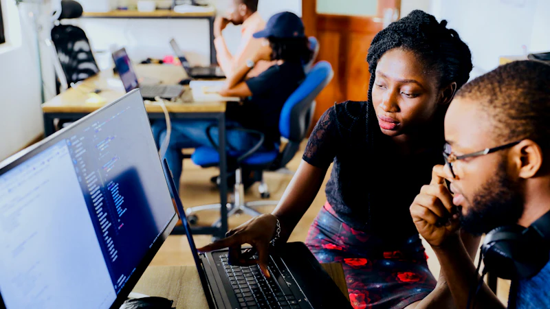 Two colleagues looking at code on a laptop screen