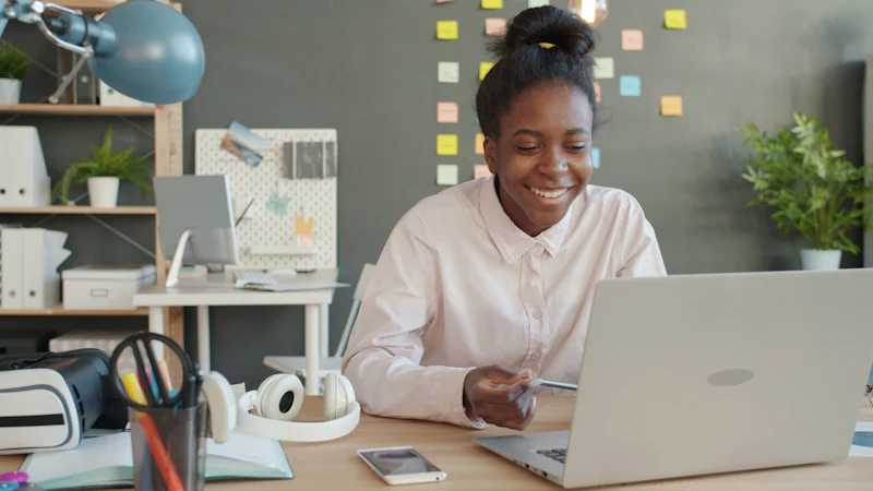 Someone smiling while working at a laptop at a tidy desk