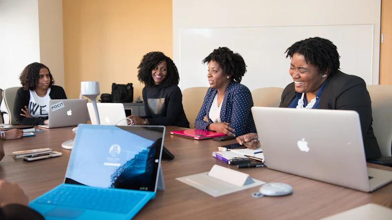 A group meeting around a conference table with laptops
