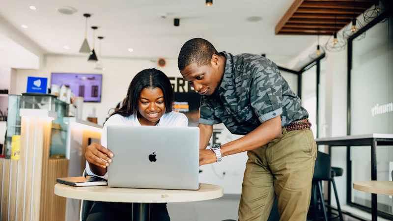 Two colleagues working through a problem at a laptop